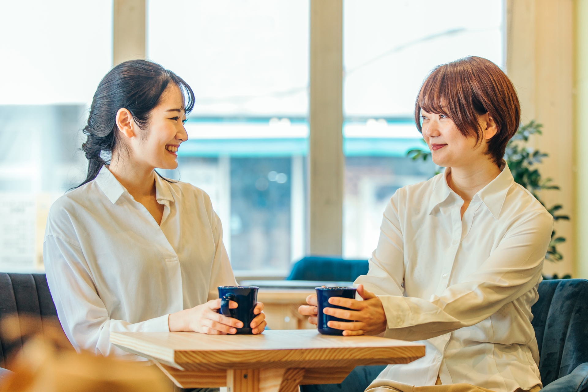職場またはカフェでコーヒーを飲みながら楽しく話している2人の女性