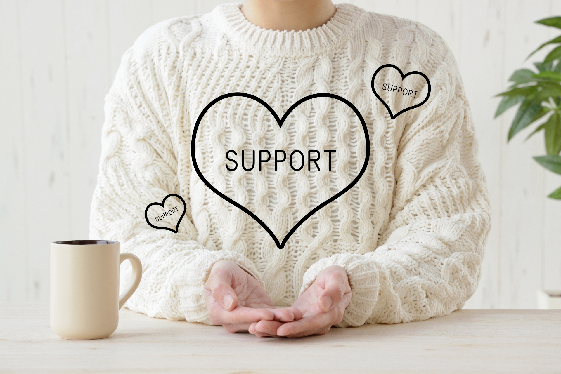 ハート型の「SUPPORT」という文字が描かれたグラフィックの中で両手を開く人物