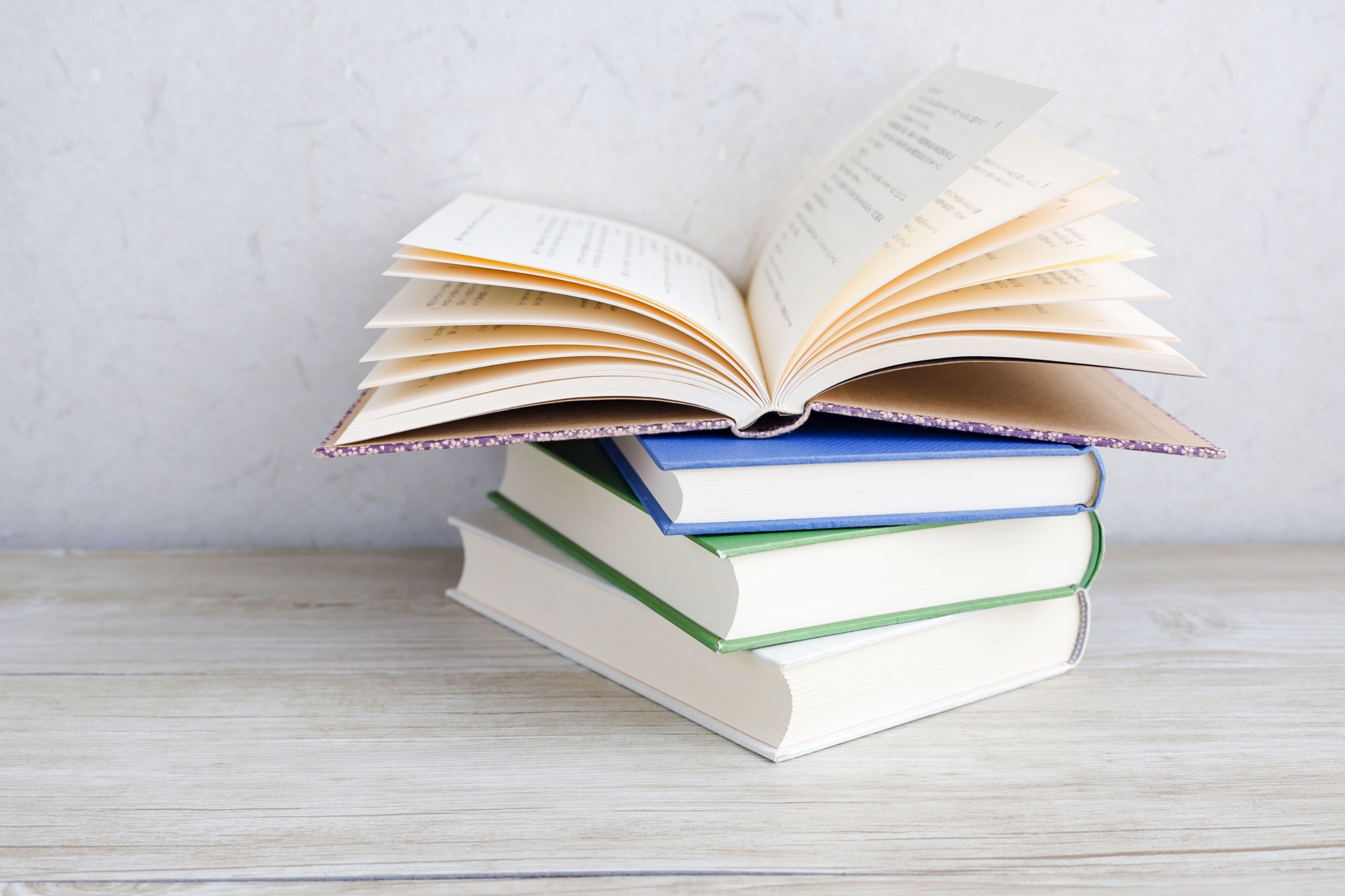 積み重ねられた本の上で開かれた小説や参考書
