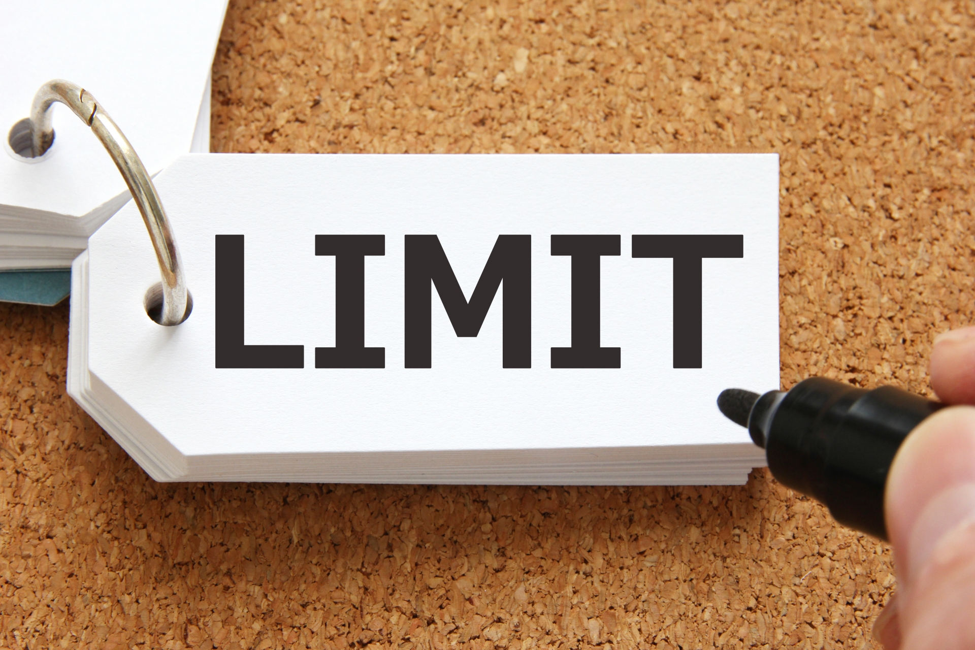 「LIMIT」と書かれた札とペンを持つ手