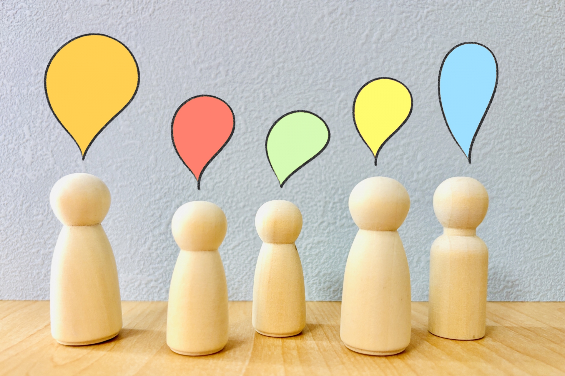 それぞれ異なる吹き出しを持つ5人の木製人形