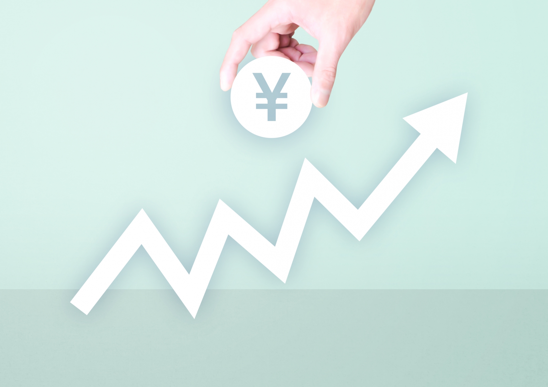 上昇する矢印のグラフの上に置かれた円形の「円 (¥)」マーク