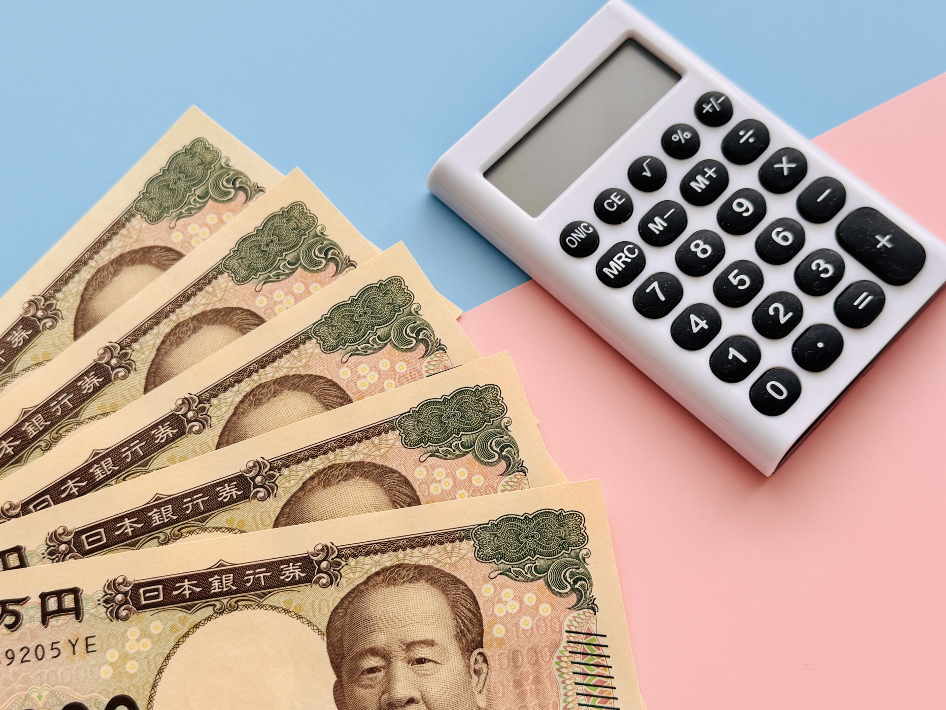 日本円の紙幣と計算機（電卓）を写した金銭・計算のイメージ