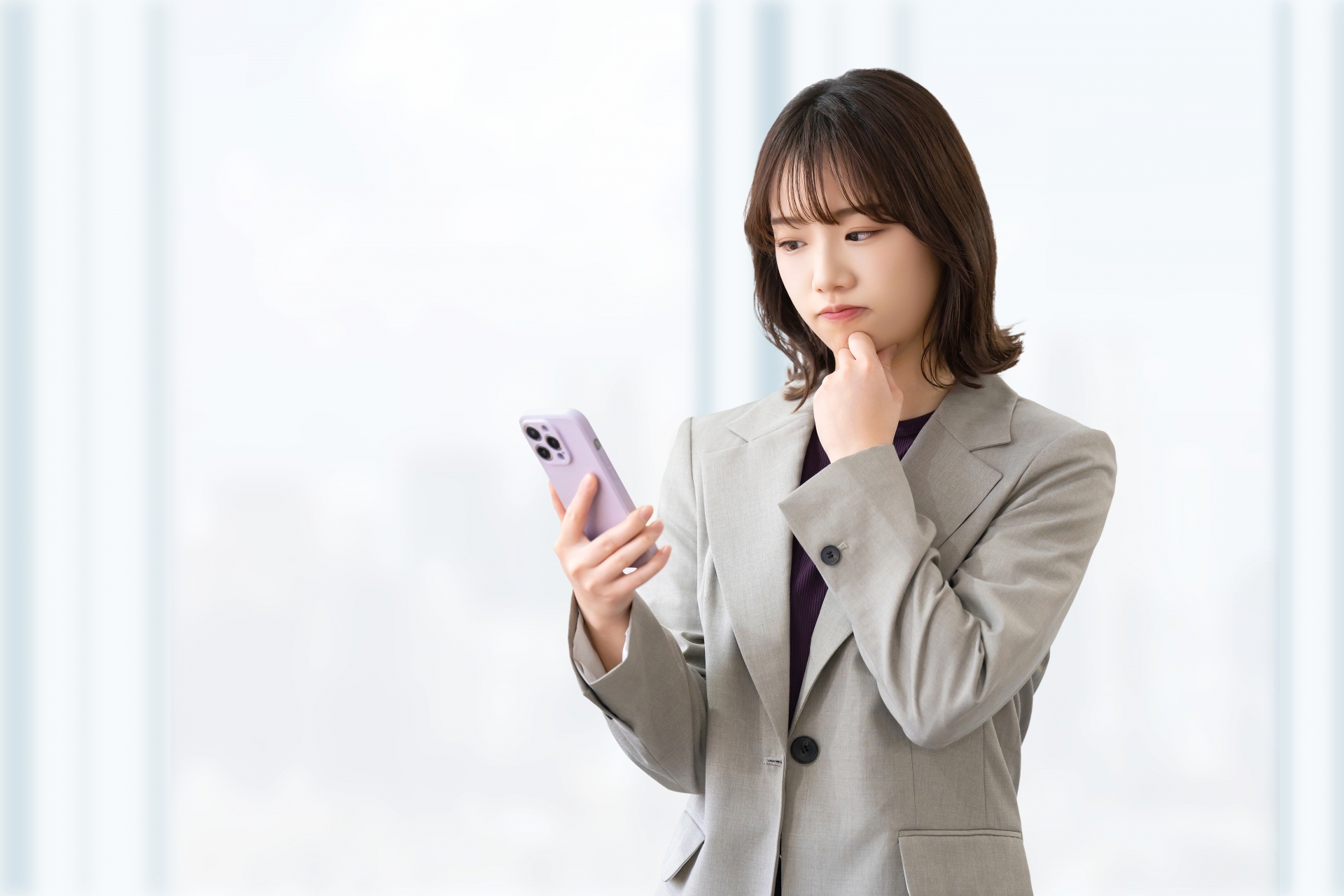 スマートフォンを見て考え込む若い女性