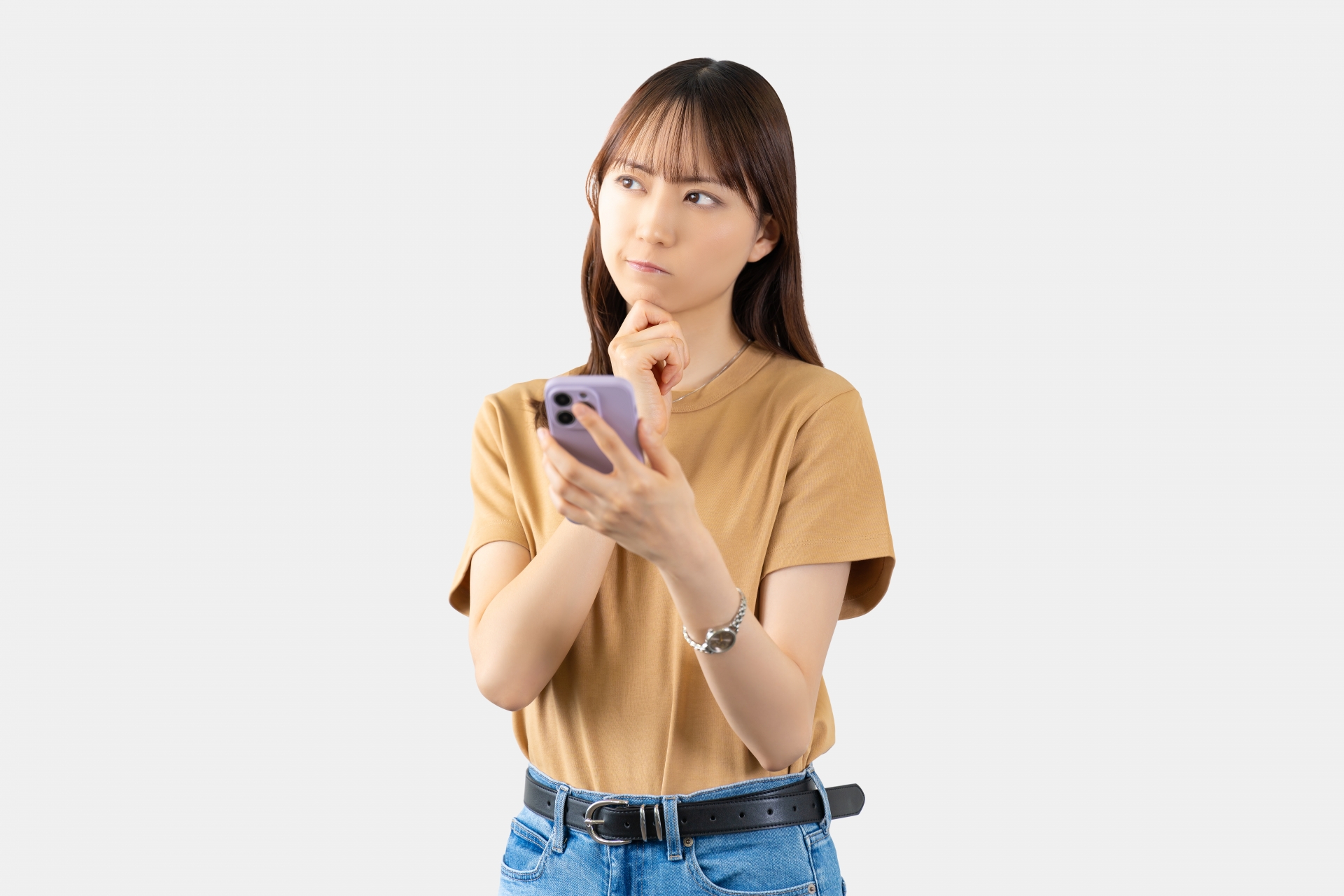 スマートフォンを持ち、思案している様子の若い女性のイメージ