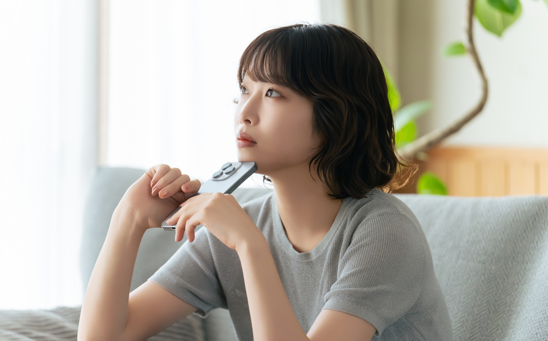 リモコンを持ち、考えごとをしている女性の横顔