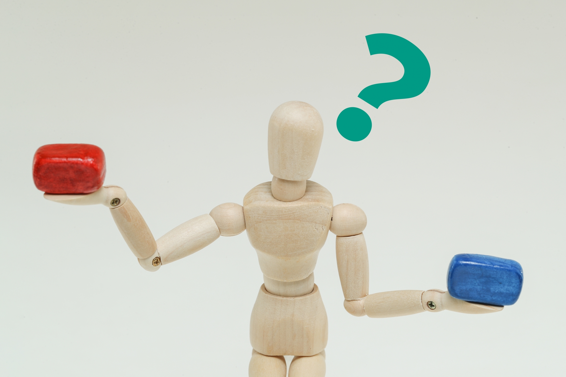 比較を表現する赤と青のブロックを両手に持つ木製の人形